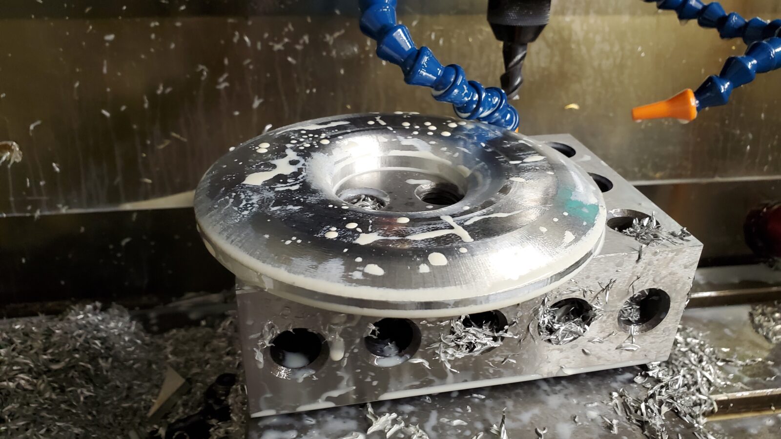 3-axis 3D contour milling of a round aluminum part on a CNC mill, with coolant lines and aluminum chips