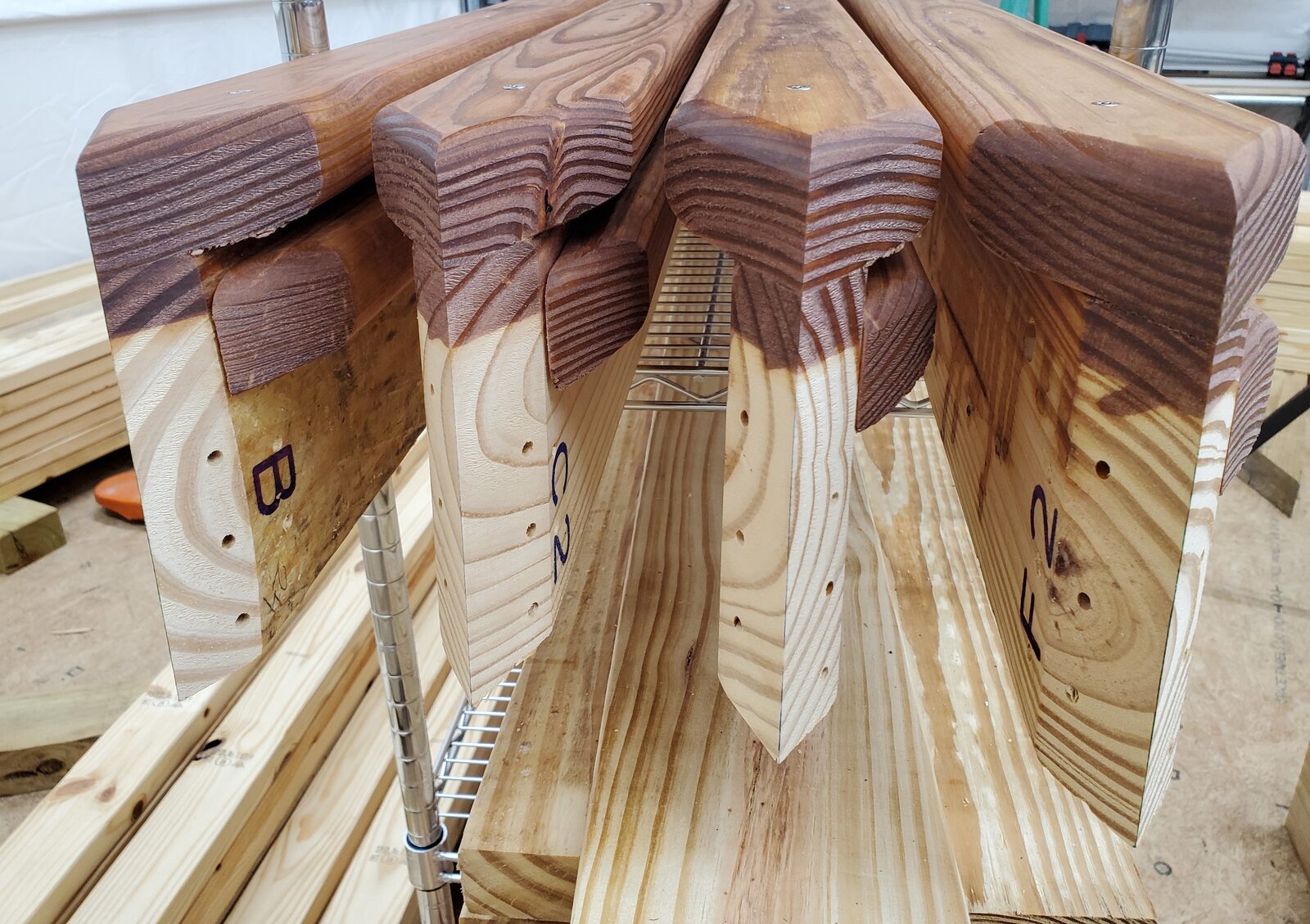 Ends of wooden dome-house struts with double compound miters, angle-drilled holes and marked part labels B, C2 and F2