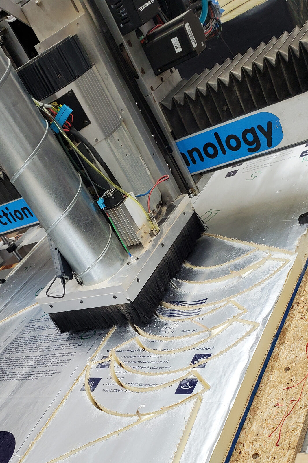 CNC router cutting curved segments from a foil-faced polyiso foam insulation sheet