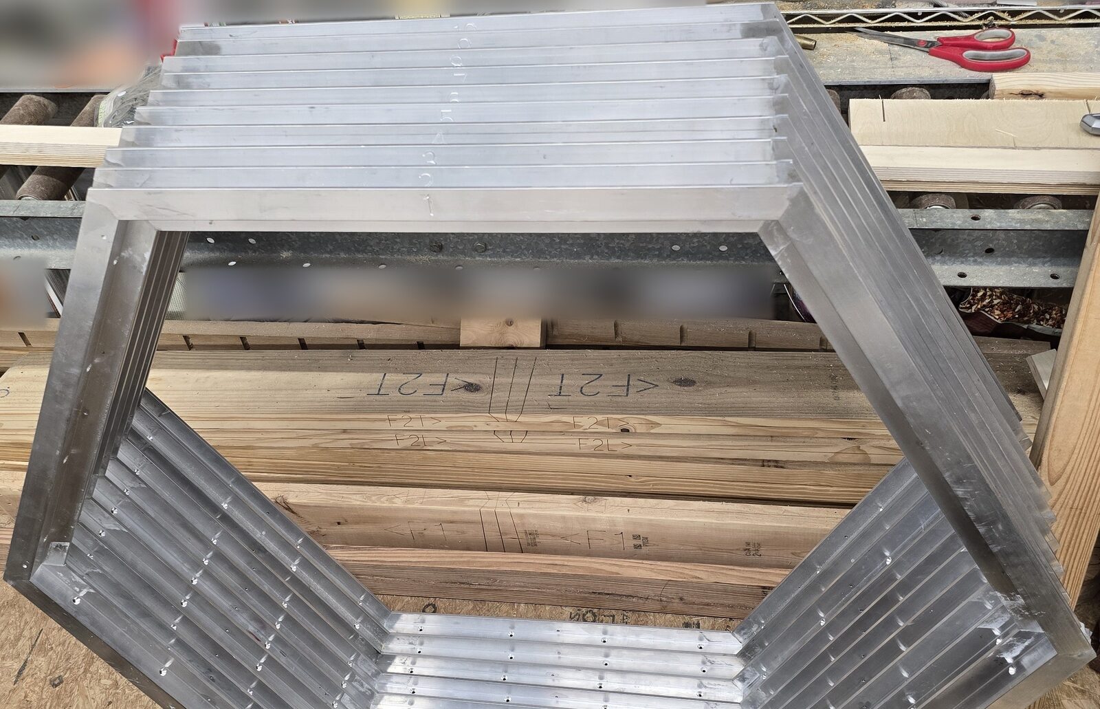 Stack of nested welded aluminum hexagon frames on a shop bench